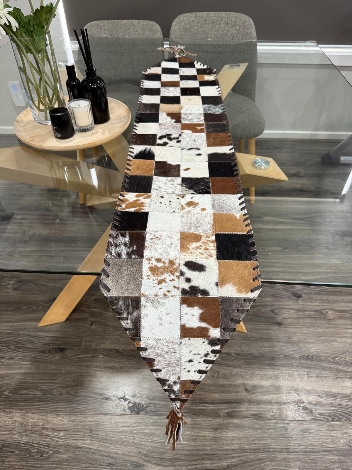 Patchwork cowhide runner on a wooden table with a modern interior setting.