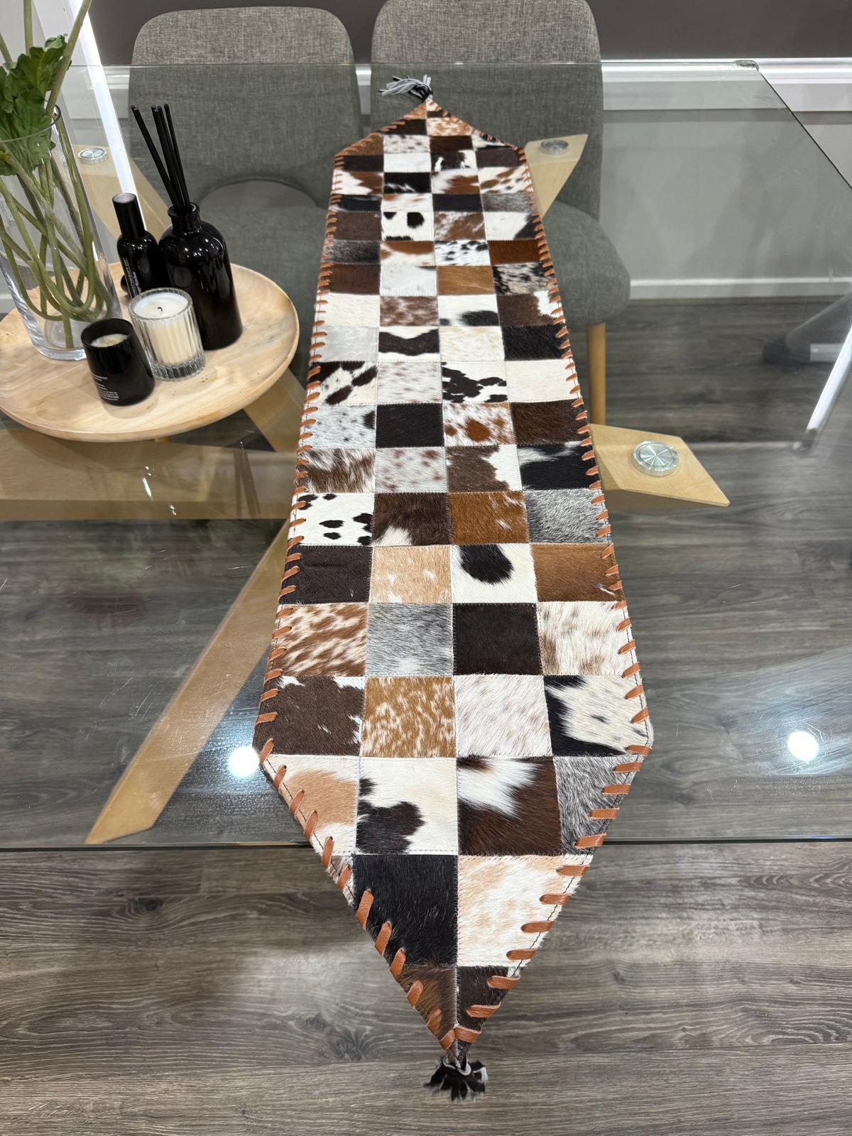 Checkered cowhide rug on a wooden floor with a chair and small table in the background.