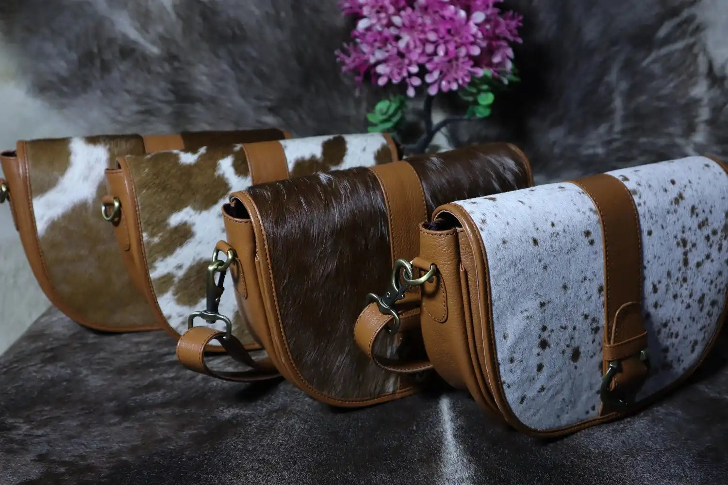 Three leather bags with cowhide pattern on a textured surface
