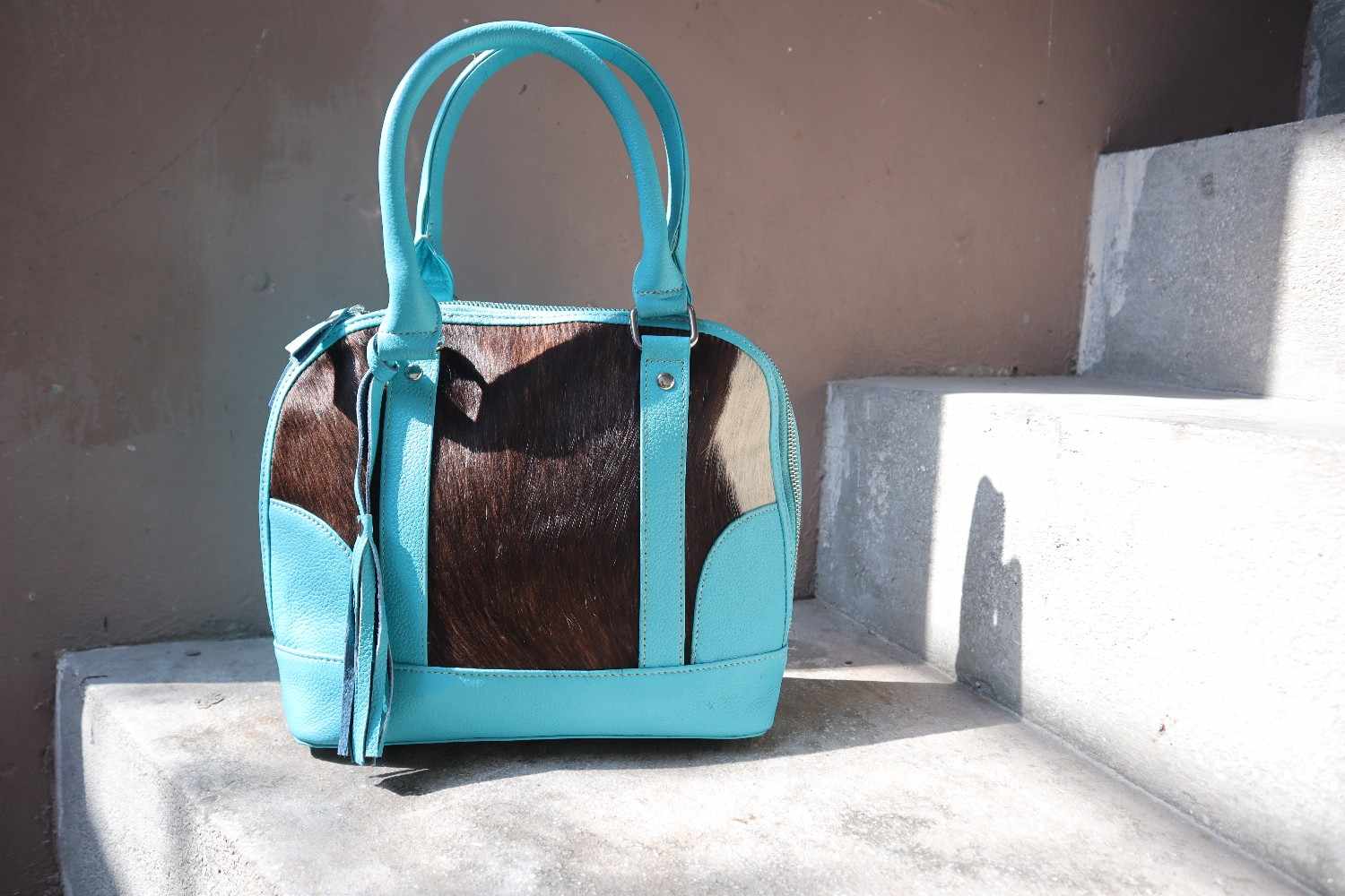 Turquoise pet carrier with a brown interior on a concrete surface.