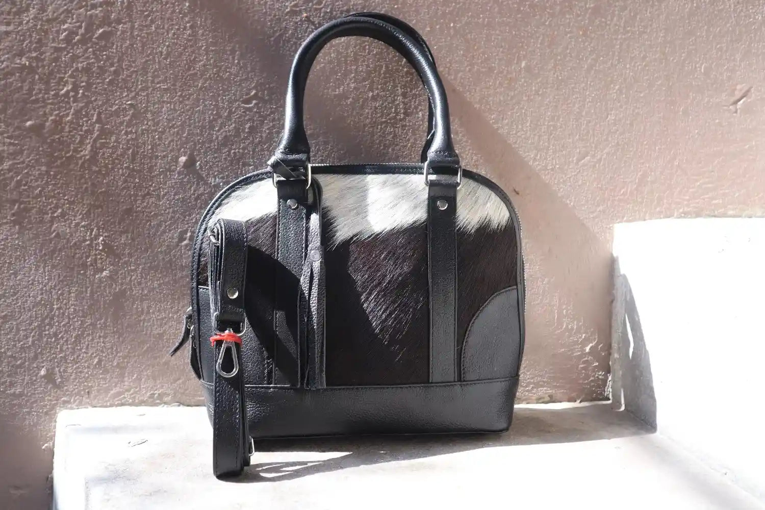 Black handbag with cowhide pattern on a textured surface