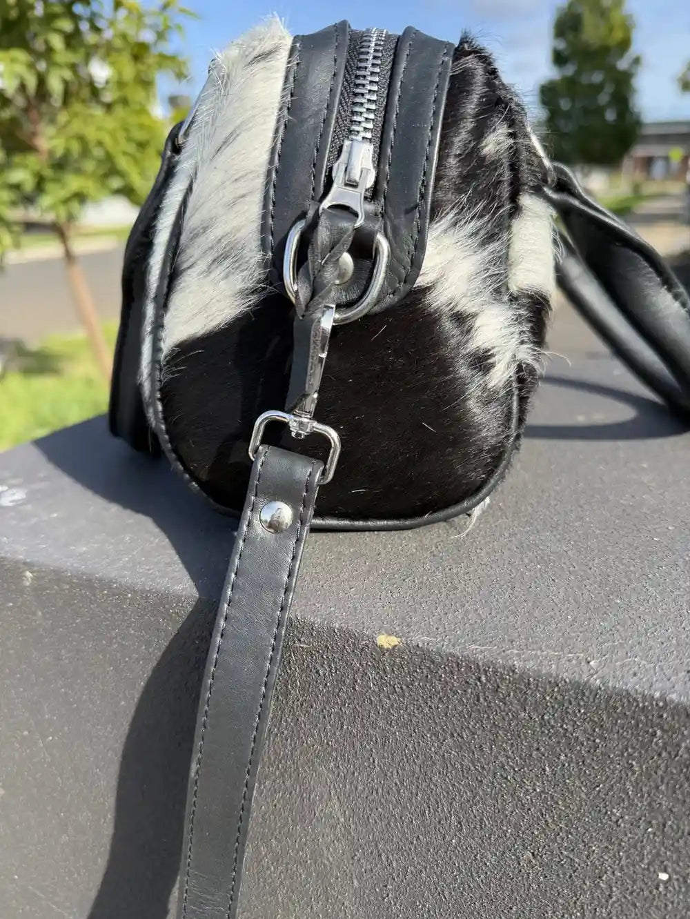 Black and white patterned handbag with a zipper on a textured surface