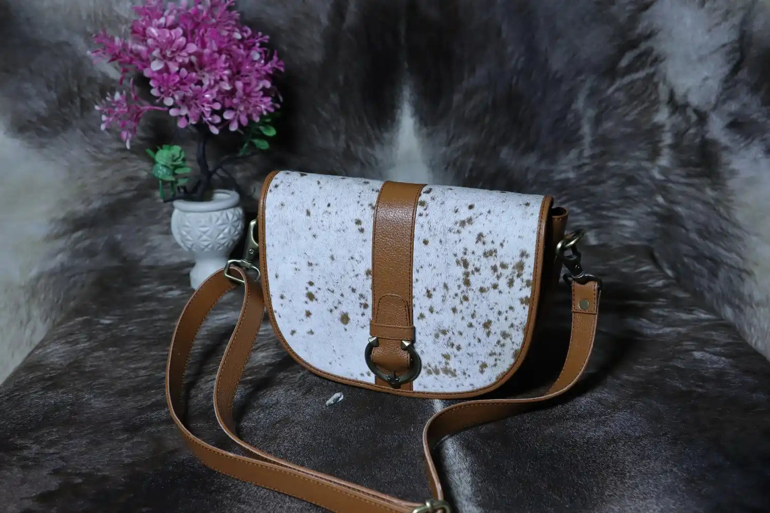 White leather bag with brown accents on a textured gray surface
