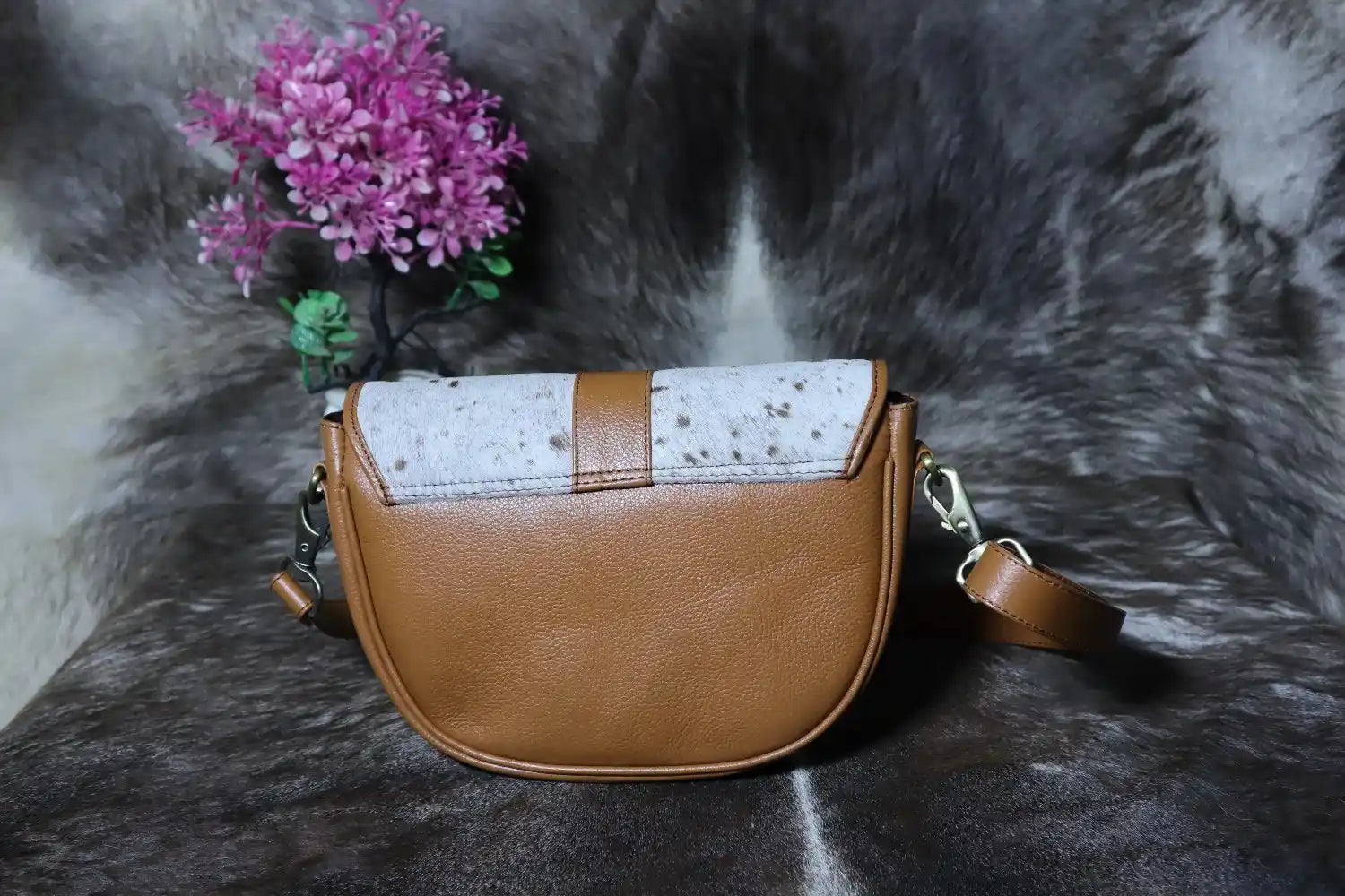 Brown leather handbag with white patterned flap on a fur surface