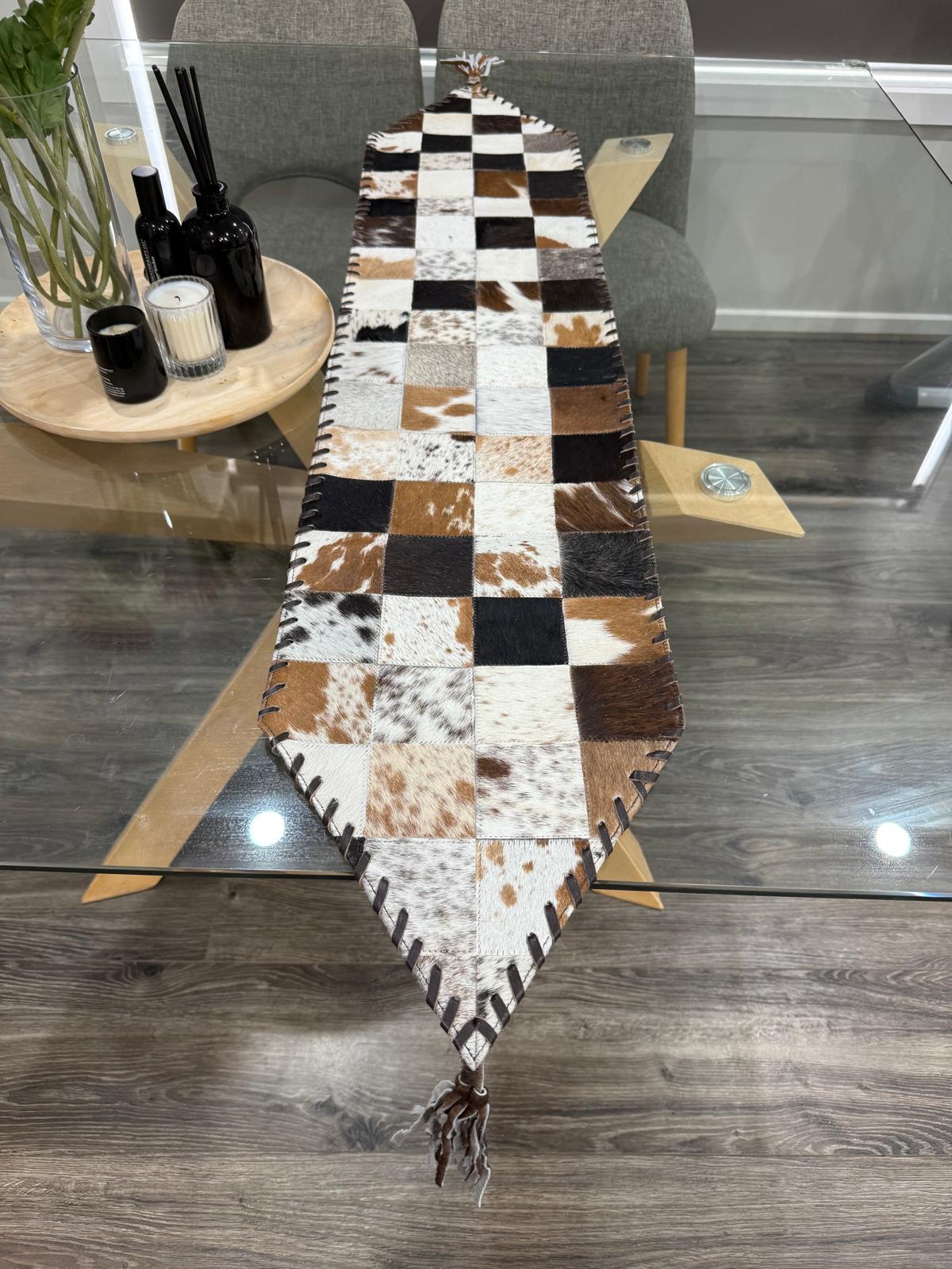 Checkered cowhide rug on a wooden floor with a gray chair and small table in the background.