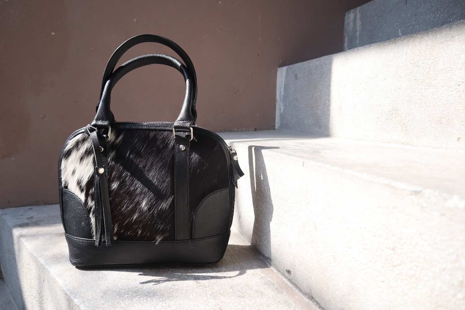 Black and brown cowhide handbag on concrete steps
