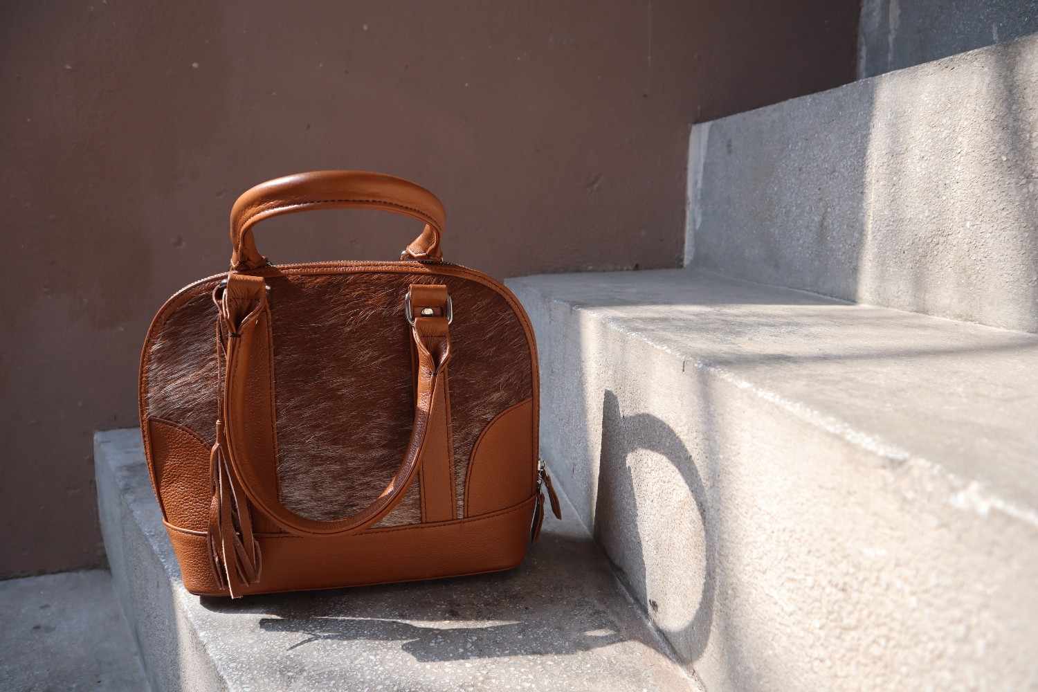 Brown leather handbag with cowhide pattern on concrete steps