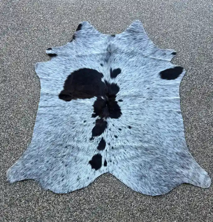 Cowhide rug with black and white pattern on a gray surface