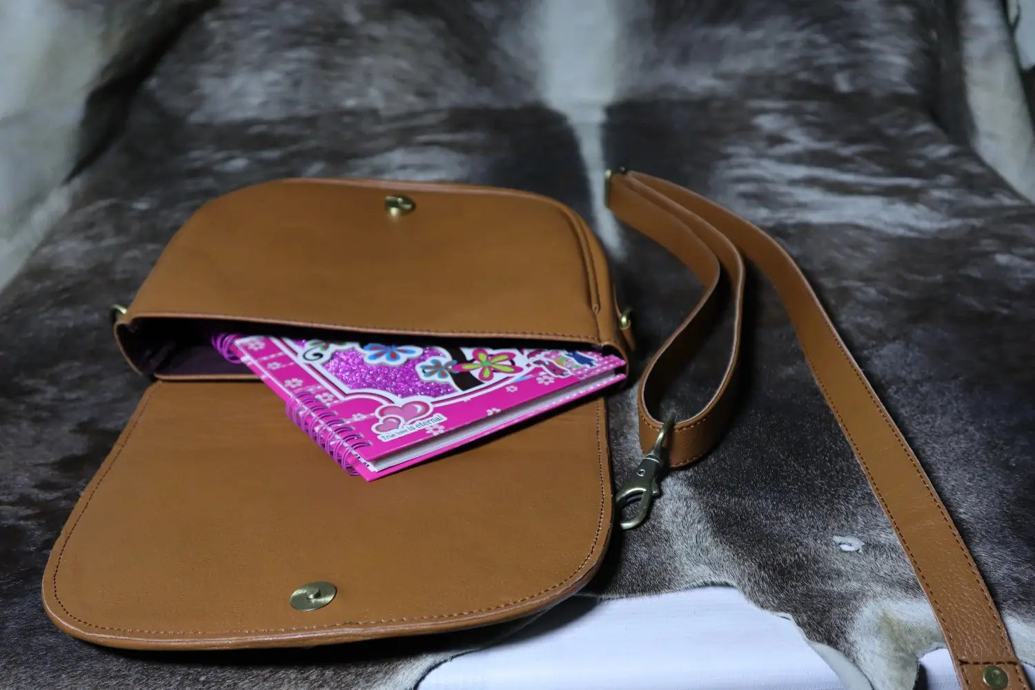 Brown leather bag with a pink patterned fabric on a textured surface