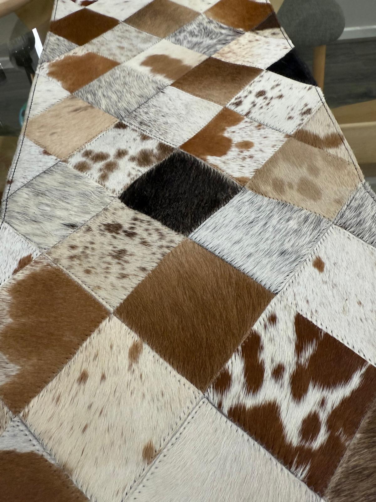 Patchwork of cowhide leather with brown, black, and white patterns.