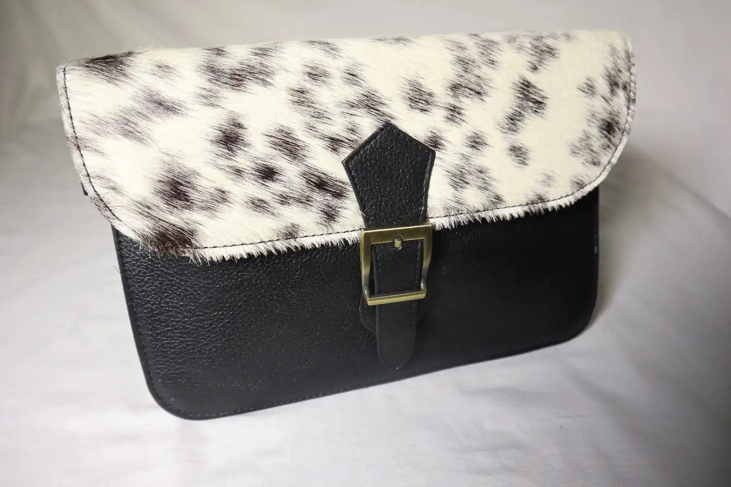 Handbag with black and white cowhide pattern on a light gray background