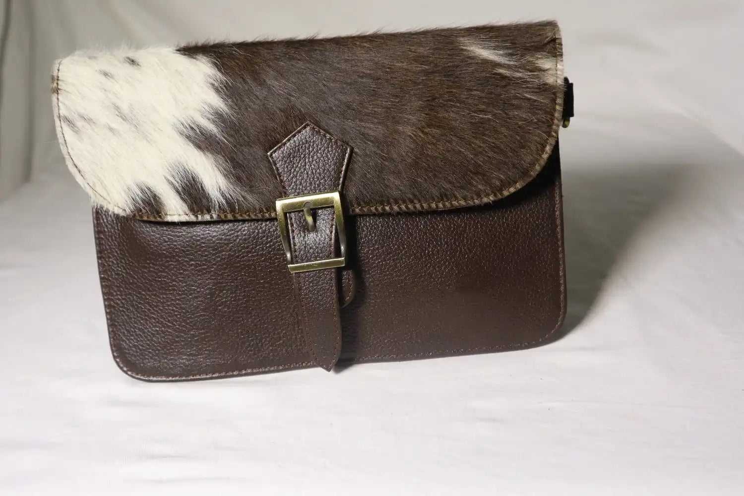 Brown leather clutch with cowhide pattern on a white background