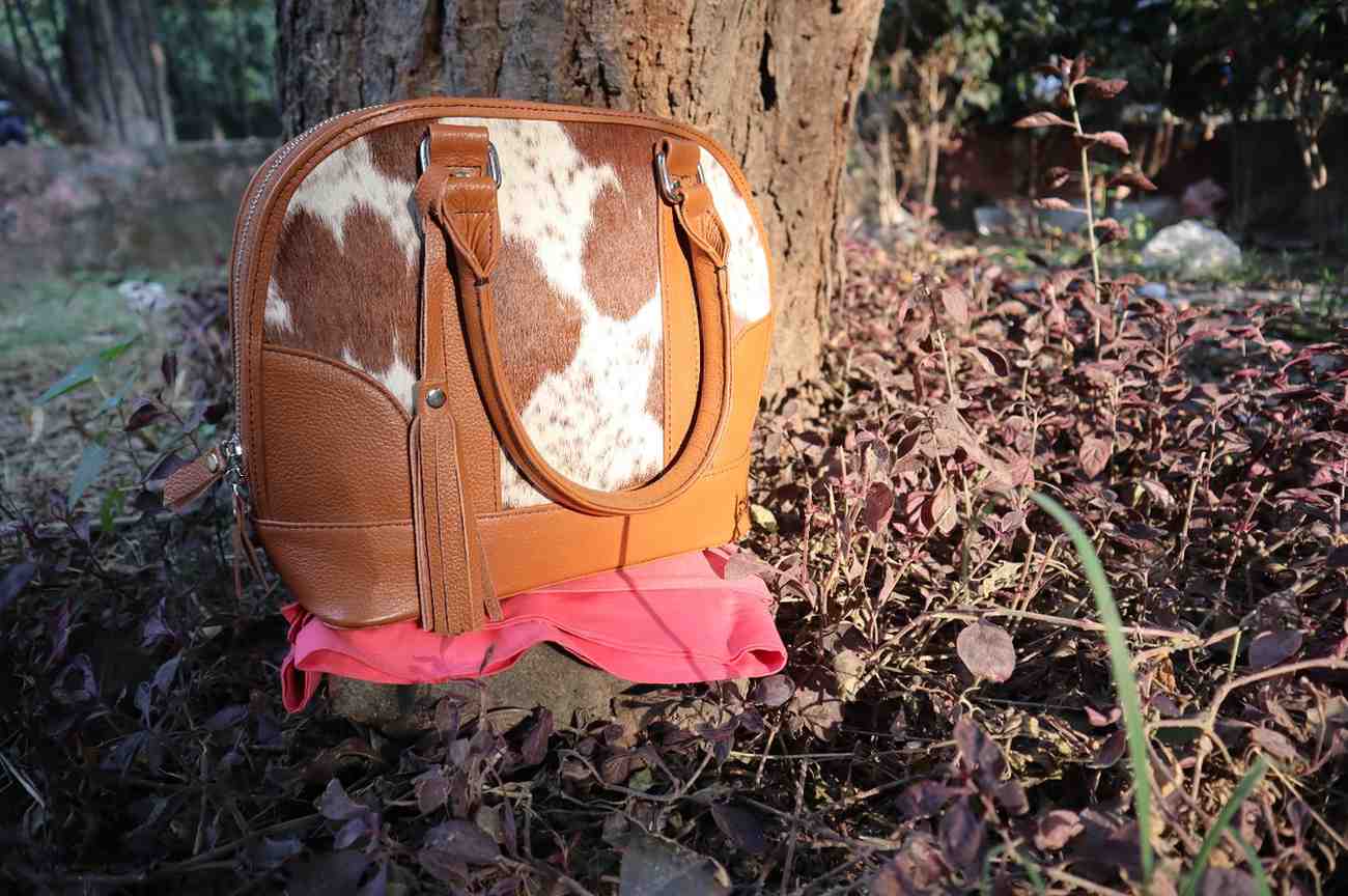 Brown and white patterned bag with pink bottom on a tree stump outdoors